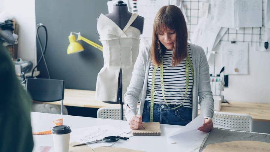 A garment being sewn from a paper pattern on a table