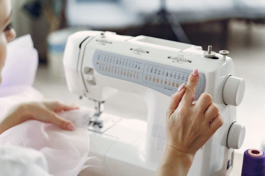 A person sewing calmly at a home machine with fabric in both hands