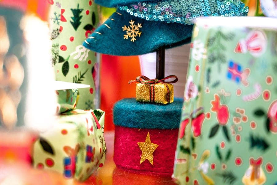 A gift wrapped in fabric and ribbon on a craft table