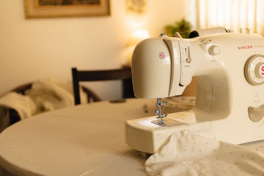 A white sewing machine on a table in a softly lit indoor room