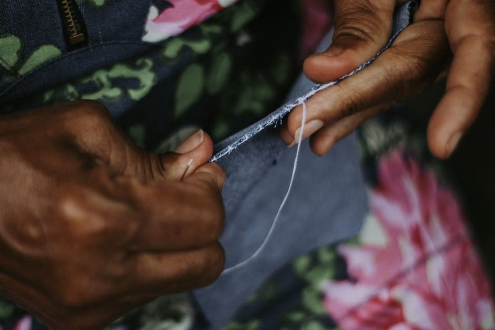A person learning to sew at a table with fabric and thread