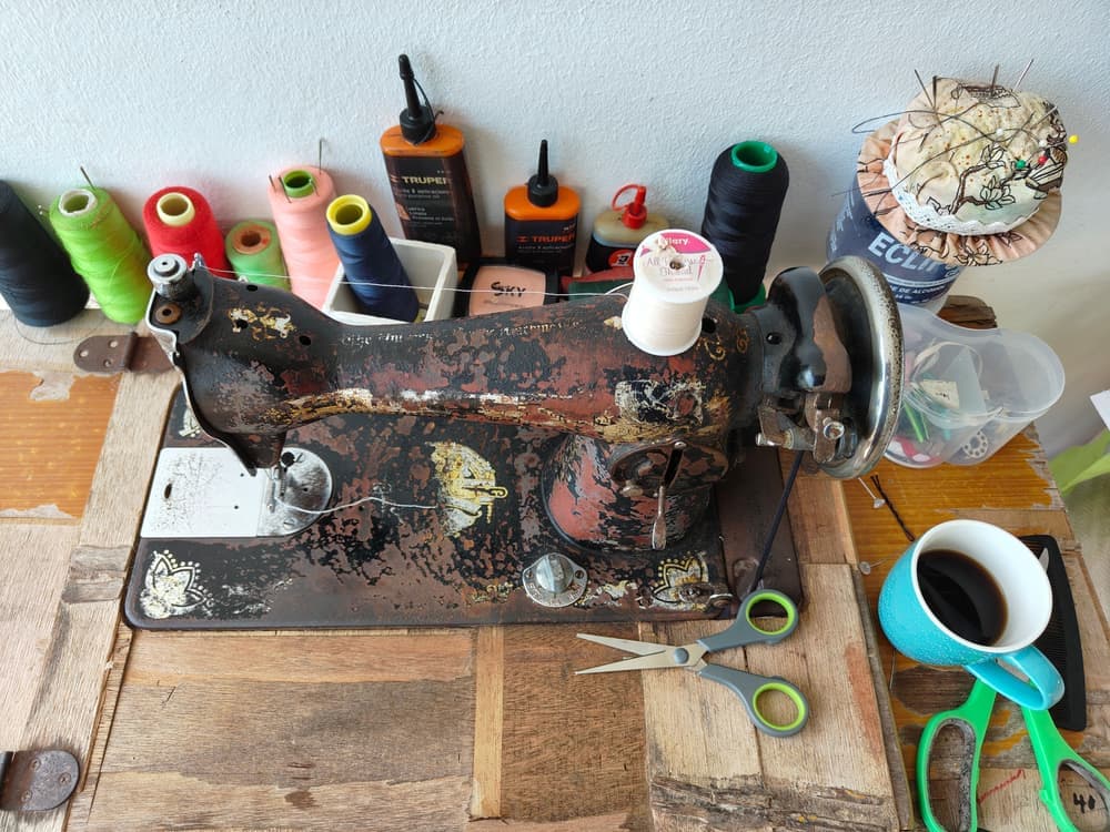 A sewing machine on a wooden table with spools of thread
