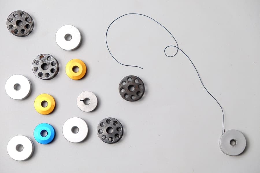 A tangle of sewing thread beside a bobbin