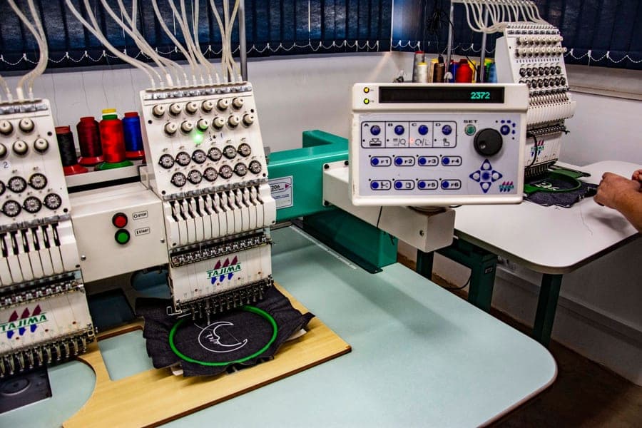 An embroidery machine stitching a design into hooped fabric