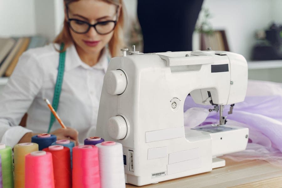 A small portable sewing machine on a table with fabric beside it