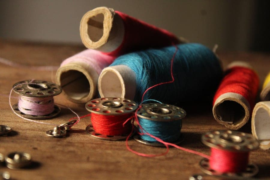 A snapped length of sewing thread beside a spool